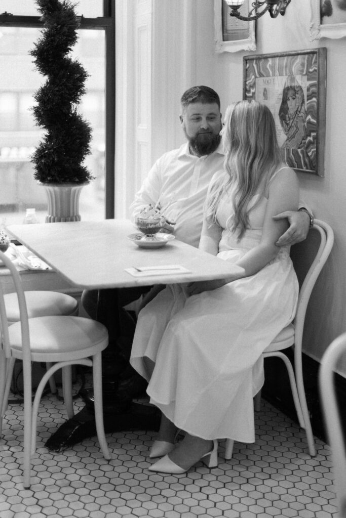 Couple sitting in Serendipity iii for engagement photos enjoying frozen hot chocolate