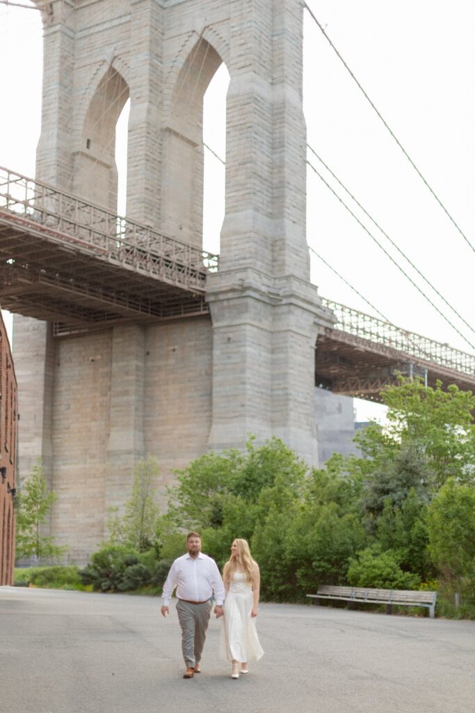 Couple during NYC engagement session in DUMBO Brooklyn with the Brooklyn Bridge in the background